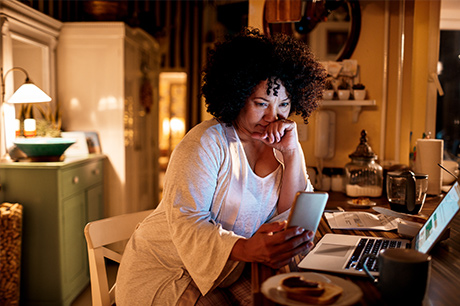 Woman at home on computer about to make a phone call
