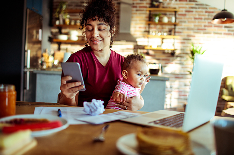 Mom holding baby at a table looking at her phone using the MyGeisinger Patient Portal